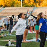 students standing and stretching during yoga on the football field